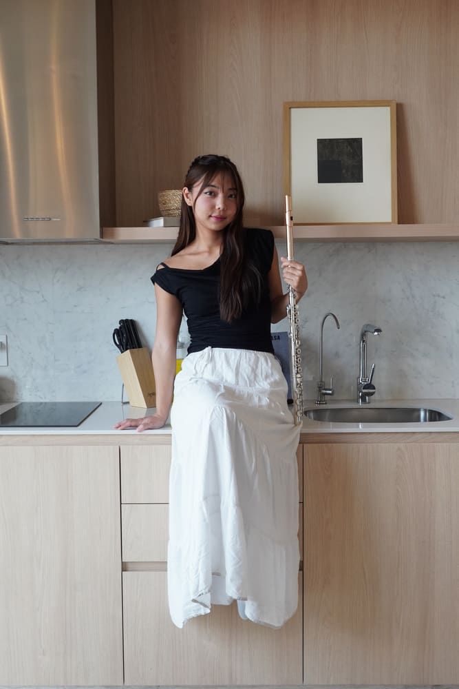 Monica holding her flute in a bright kitchen