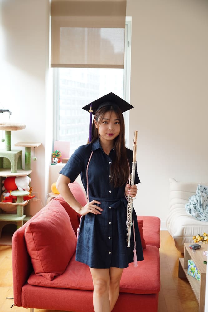 Monica in a graduation cap holding her flute