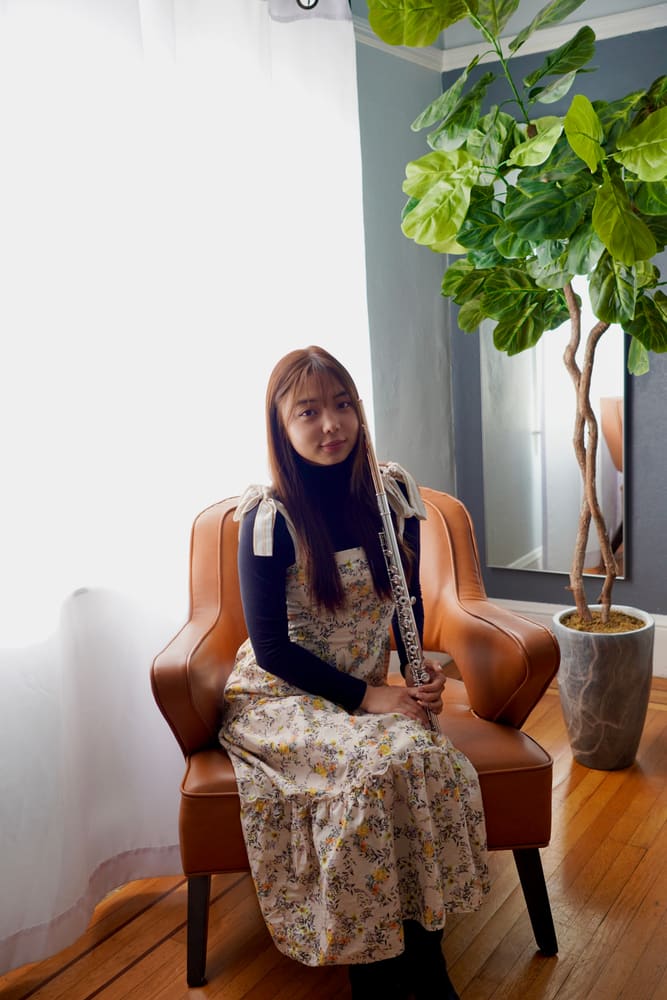 Monica seated in a leather armchair with her flute